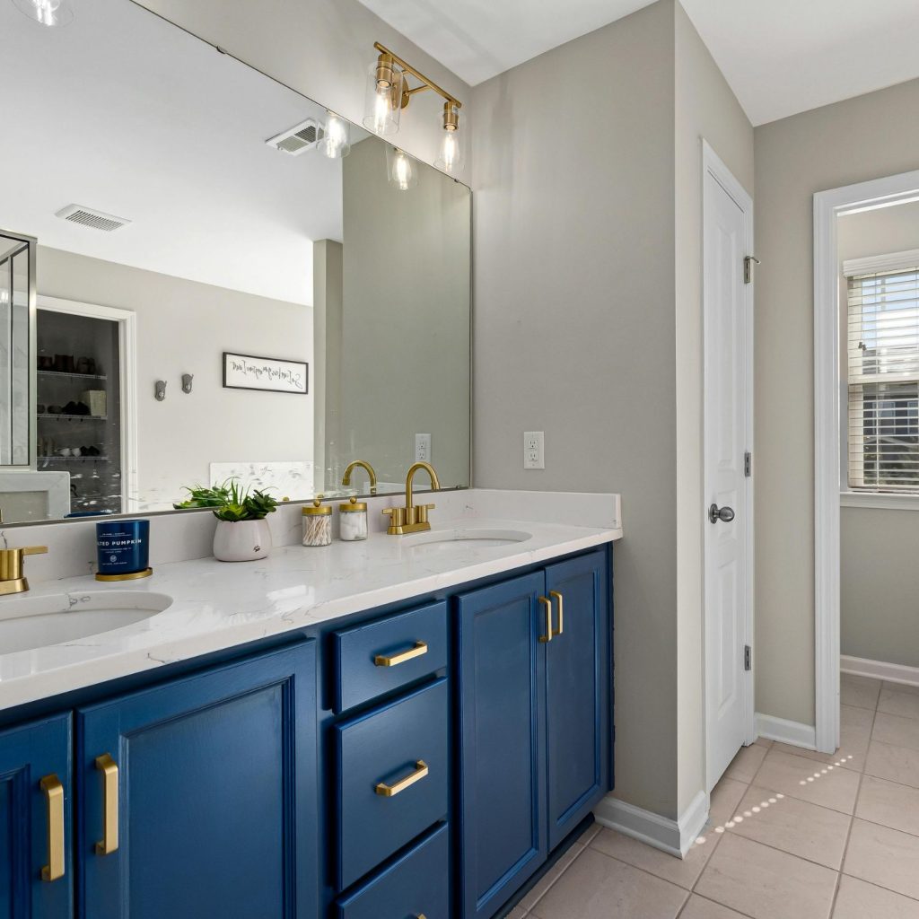 A navy blue double vanity with a white stone benchtop and brass tapware, custom made for a Sydney bathroom renovation by 10X Joinery.