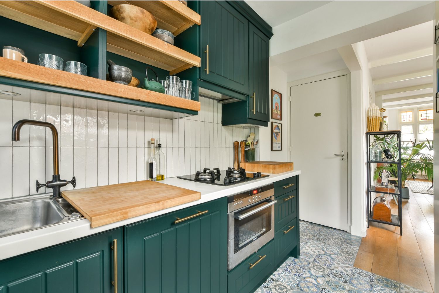 A kitchen renovation in Blacktown with deep green shaker cabinets, timber open shelving, white vertical tiles and brass handles, designed and built by 10X Joinery.