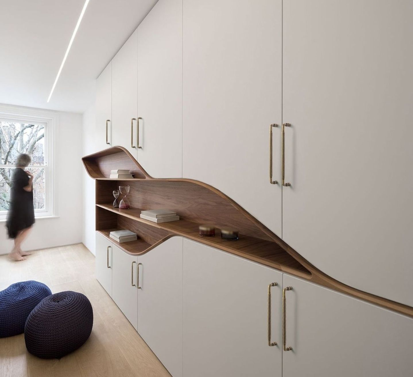 A white built-in wardrobe wall with brass handles and a sculptural walnut shelf, showing luxury custom joinery in a Sydney home by 10X Joinery.