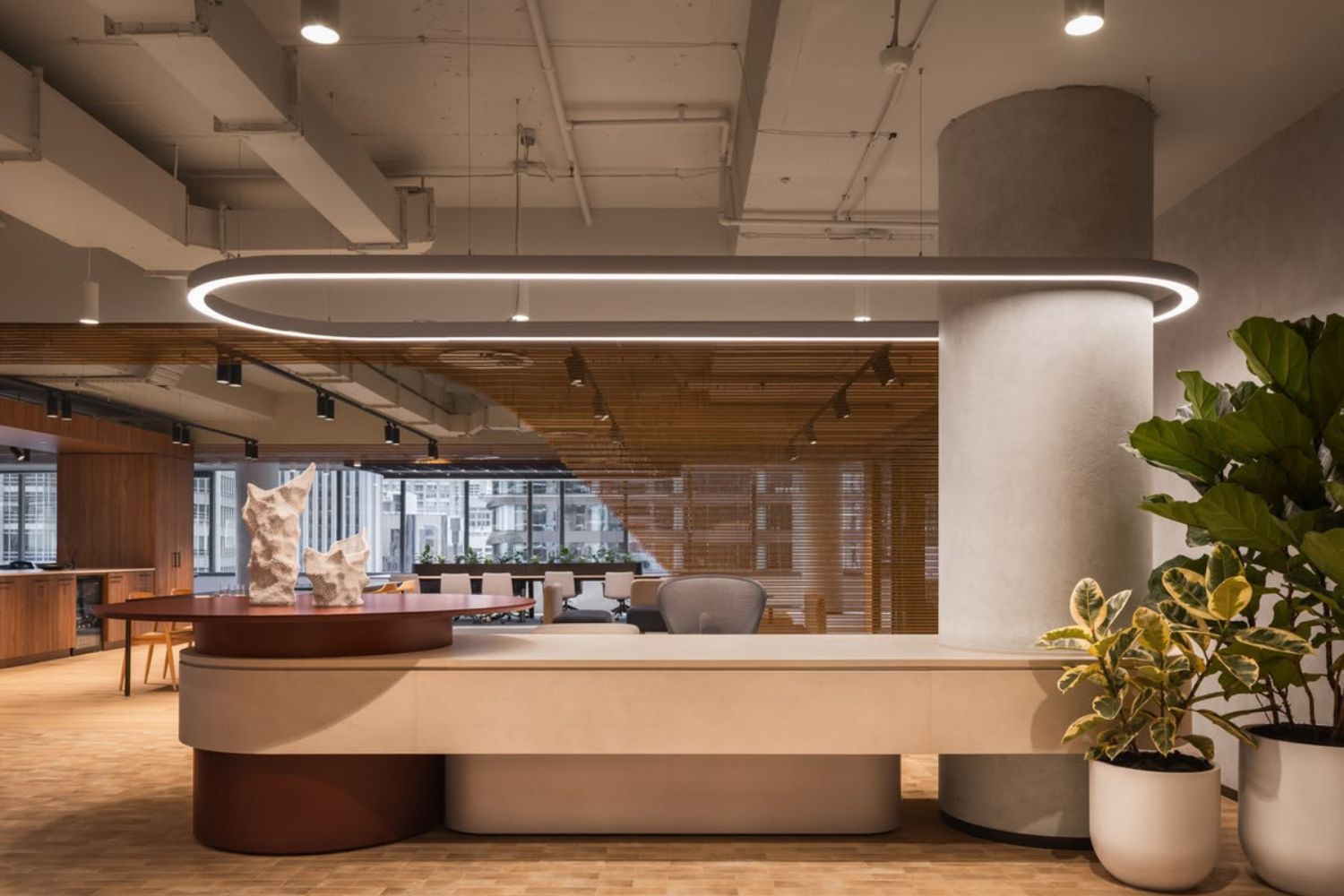 Architectural commercial joinery in a Sydney office, with a curved stone reception counter, timber batten ceiling and oval LED pendant, designed and built by 10X Joinery.