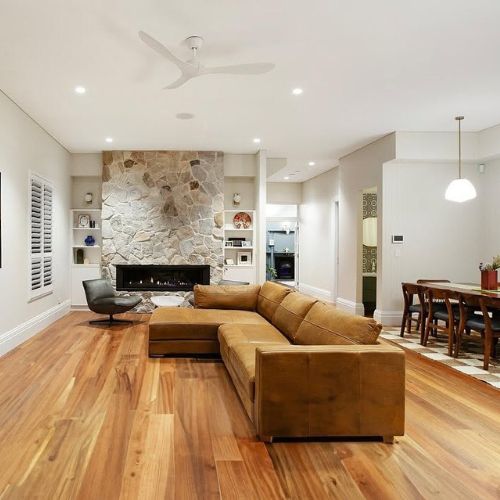 Open-plan living room with custom stone fireplace and built-in joinery designed with an architect by 10x Joinery