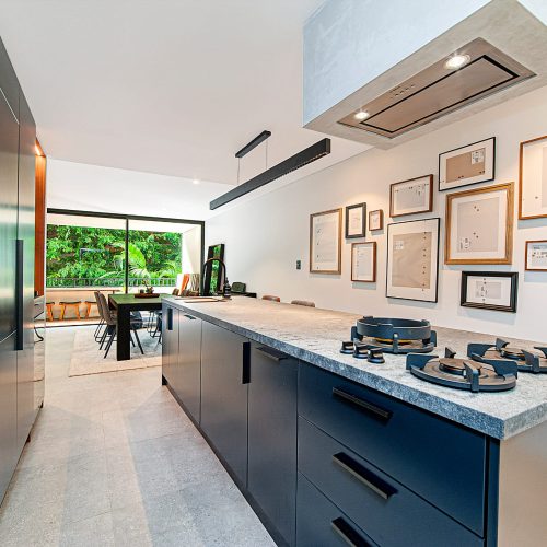 A renovated Sydney kitchen with dark navy cabinets and a long stone benchtop opening onto the dining area, coordinated and installed by 10X Joinery.