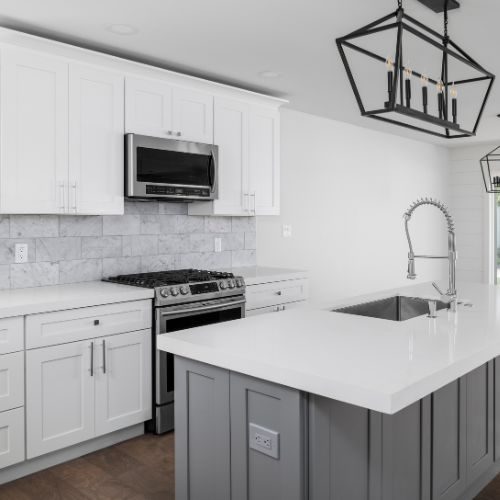 A compact apartment kitchen near Auburn station with white shaker cabinets, a grey island and stone benchtop, making the most of a small space by 10X Joinery.
