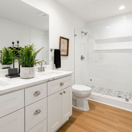 A white shaker-style vanity with built-in drawers and a recessed shower niche for extra bathroom storage by 10X Joinery.