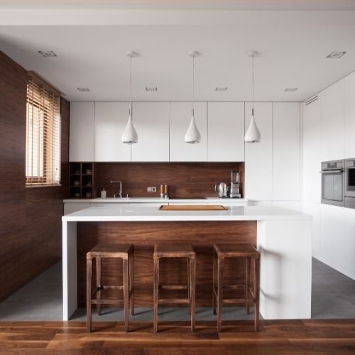 A white handleless kitchen with a timber-panelled island, pendant lights and full-height storage for a busy Baulkham Hills family by 10X Joinery.
