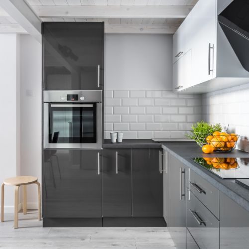 A builder-grade kitchen upgrade in a newer Blacktown-area estate, with charcoal gloss cabinetry, a built-in oven and grey benchtops by 10X Joinery.