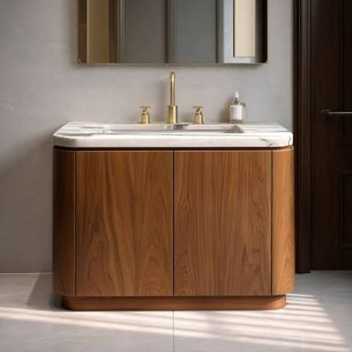 A curved timber vanity with a white stone benchtop and brass tapware, crafted with profiled fronts by 10X Joinery.
