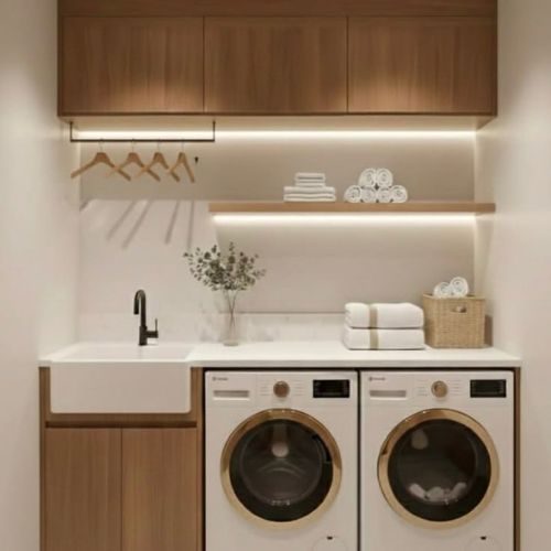 Custom laundry cabinetry with timber overhead cupboards, a hanging rail and built-in washer and dryer space by 10X Joinery.