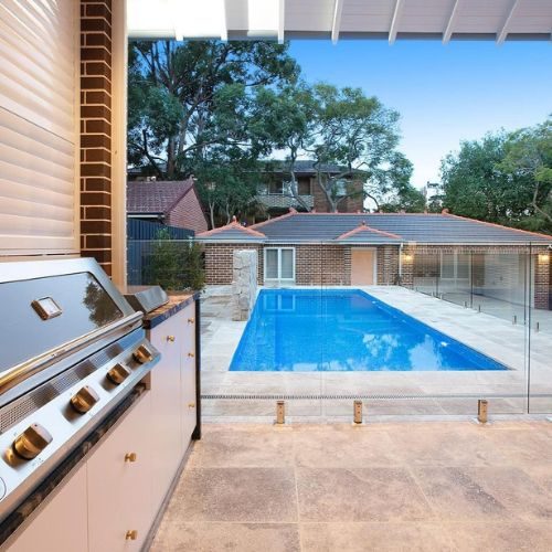 Outdoor kitchen joinery with built-in BBQ overlooking a backyard pool
