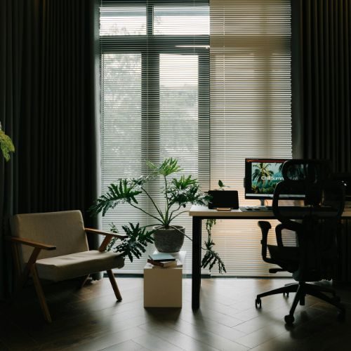 A home office desk facing large windows with an ergonomic chair and lounge seating, designed and installed in-house for a Sydney home by 10X Joinery.
