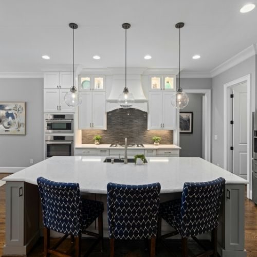 A large white kitchen island with seating and pendant lights, sized for a Baulkham Hills family home by 10X Joinery.