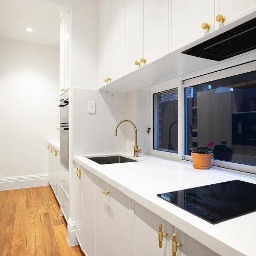 White new build kitchen with brass handles and window splashback by 10X Joinery Sydney