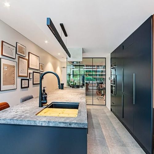 Renovated kitchen with navy cabinetry, stone island benchtop and integrated sink