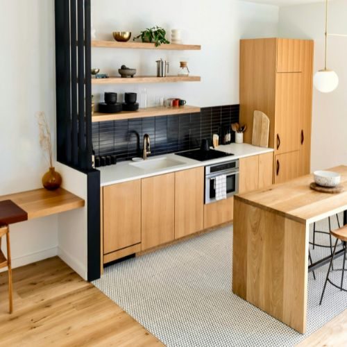 An Auburn kitchen makeover with light timber cabinetry, a black tiled splashback and floating timber shelves by 10X Joinery.