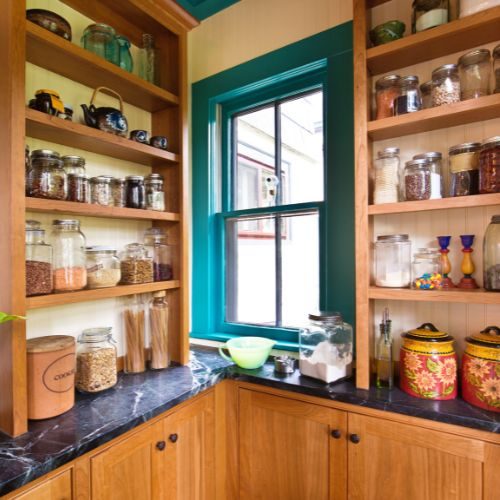 Custom timber pantry shelving wrapped around a window, keeping jars and ingredients organised in a Castle Hill kitchen by 10X Joinery.