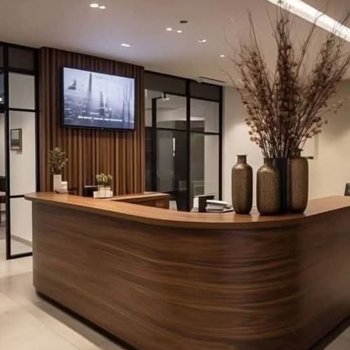 A curved timber veneer reception desk with a feature batten wall in a Sydney office foyer, custom made by 10X Joinery.