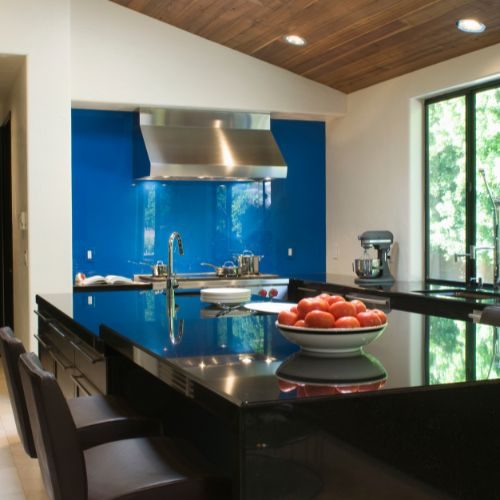 A black gloss benchtop paired with a cobalt blue glass splashback in a Bankstown kitchen by 10X Joinery.