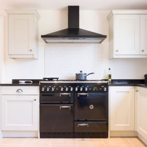 A Castle Hill kitchen upgrade with cream shaker cabinets, a black range cooker and matching rangehood by 10X Joinery.