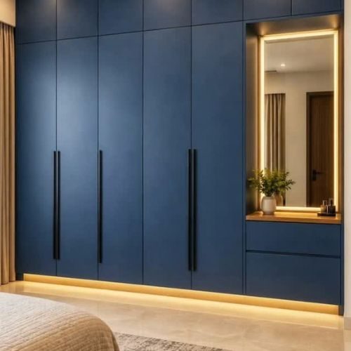 Floor-to-ceiling navy blue built-in wardrobe with long black handles and an LED-lit mirror niche, made by 10X Joinery.