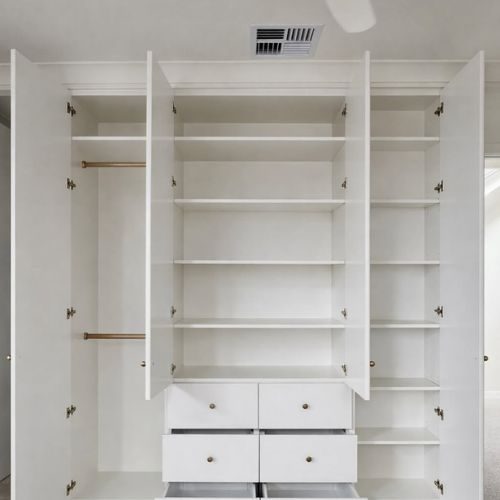 White built-in wardrobe with open doors showing shelves, hanging space and drawers