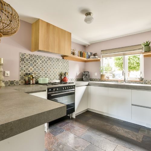 A white Blacktown kitchen with timber overhead cabinets, a concrete-look benchtop and patterned tile splashback, delivered by 10X Joinery.